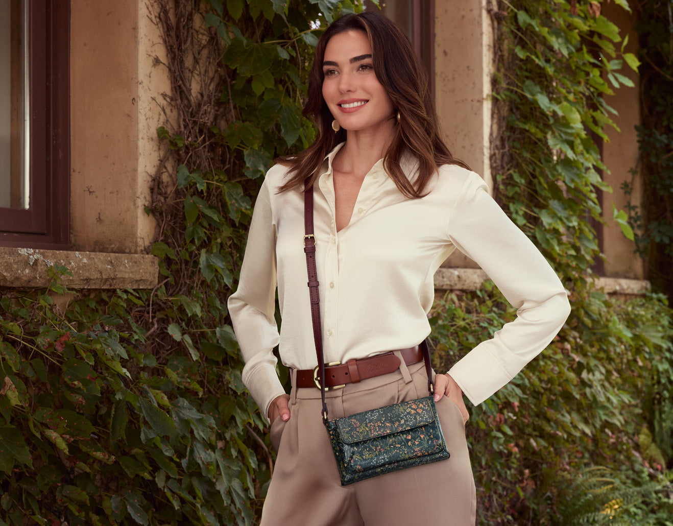 Model wearing crossbody flower bag by Patricia Nash, floral leather handbag in lifestyle setting