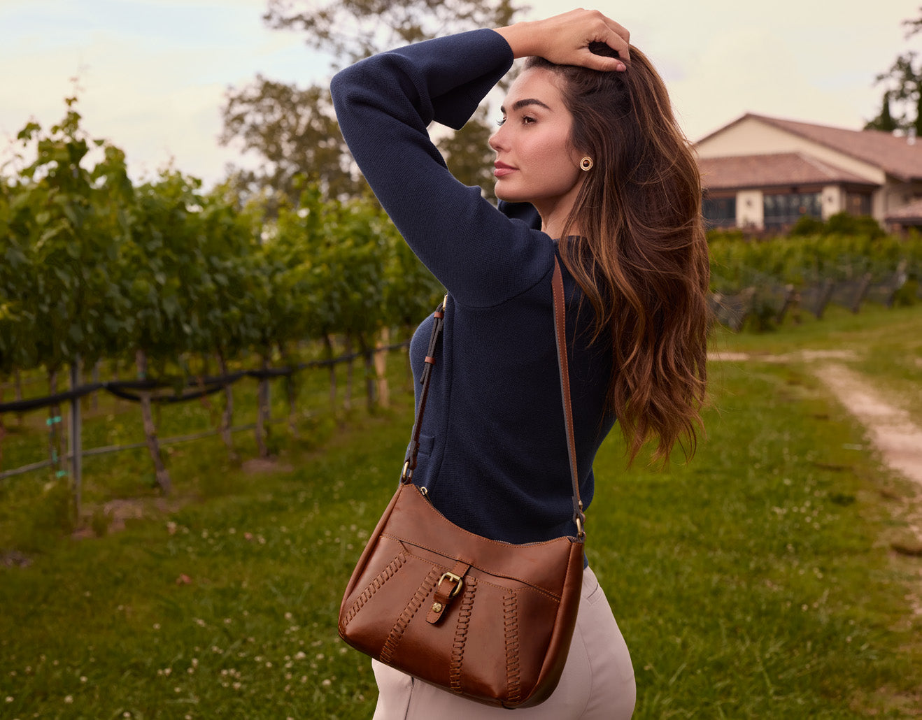 Model carrying shoulder bag by Patricia Nash, artisan leather handbag featured in lifestyle setting