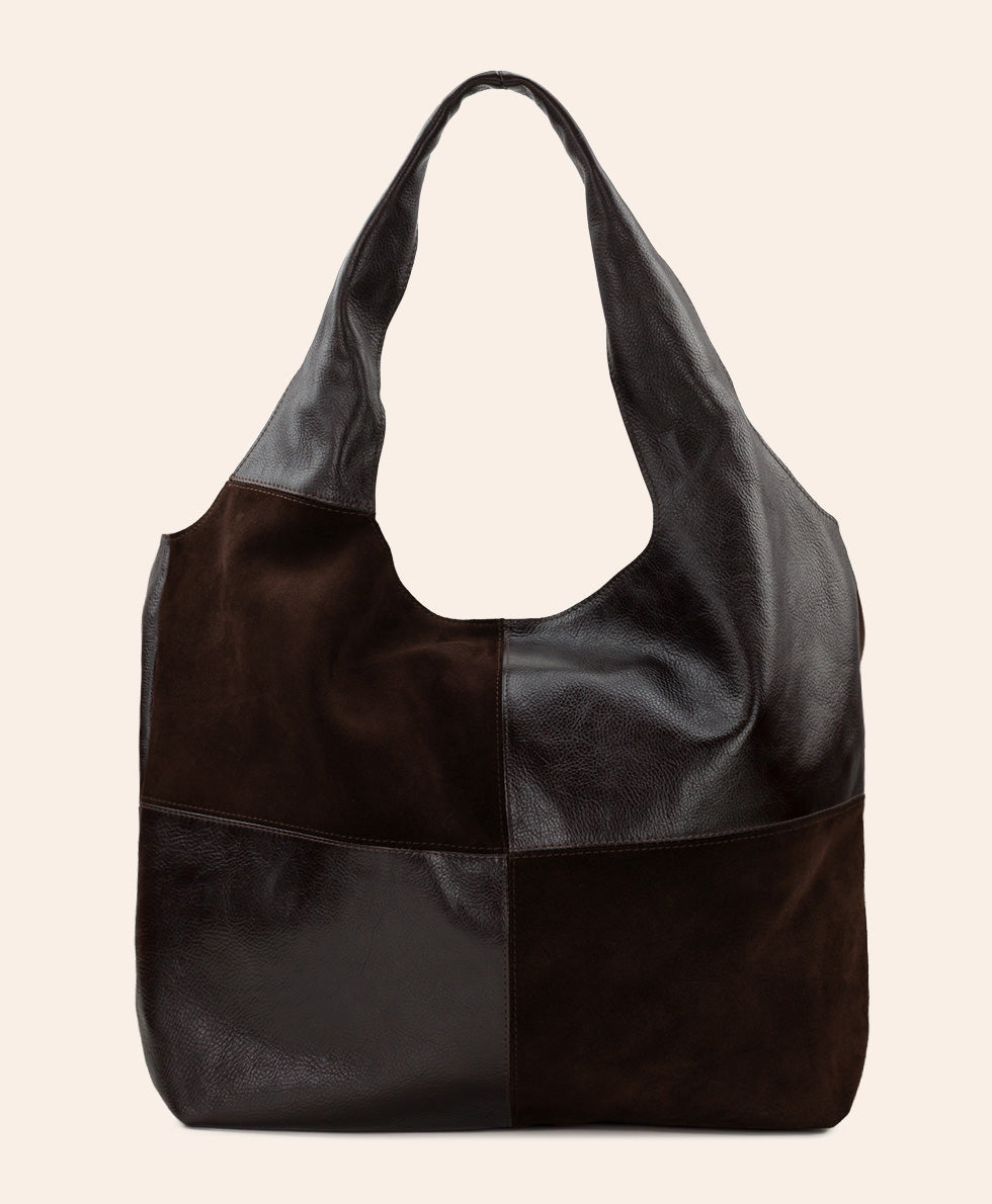 A large patchwork leather shoulder bag in dark brown and black, featuring a slouchy hobo silhouette and long handles, set against a solid off-white background.