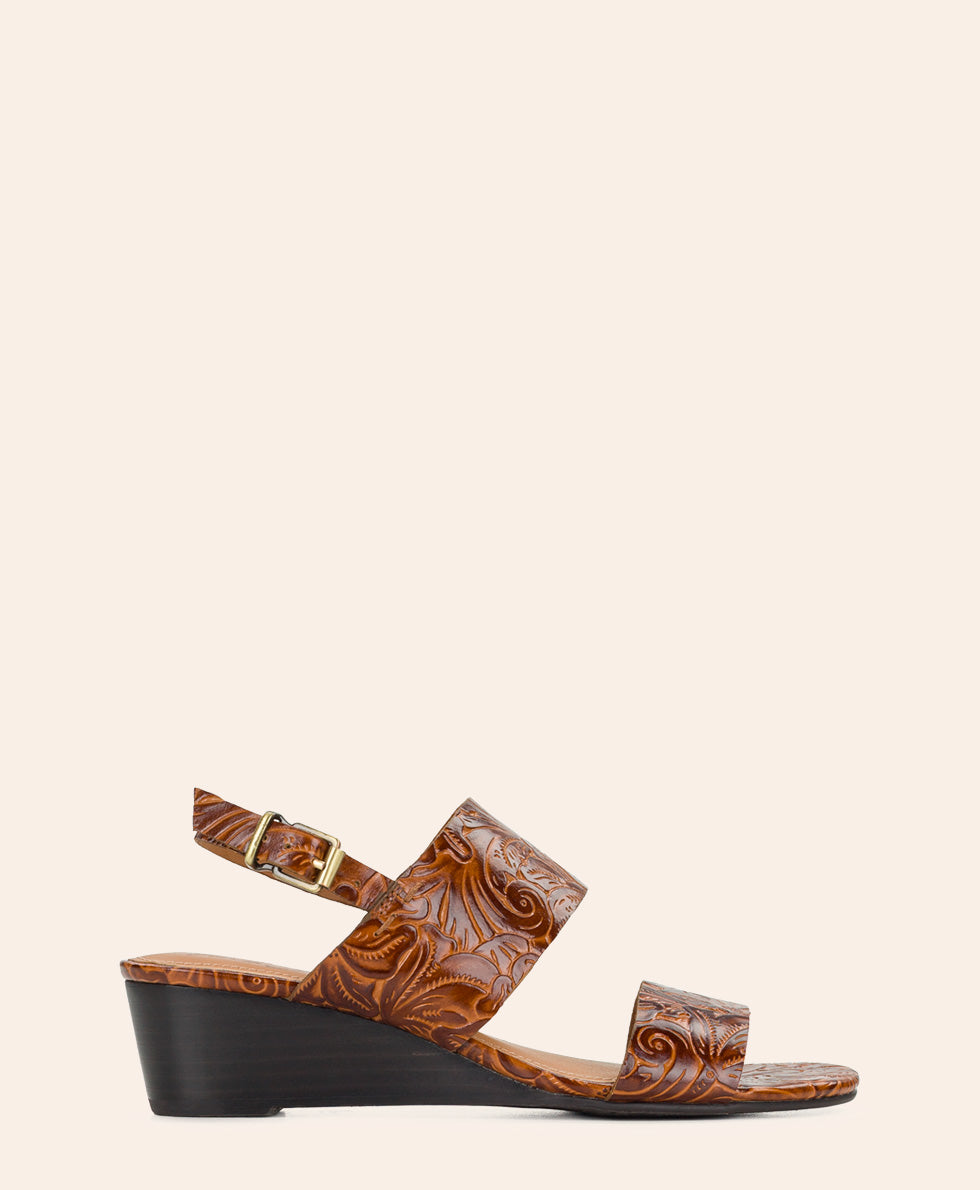 A single brown leather wedge sandal with embossed floral swirl patterns and a gold-tone buckle, shown in profile against a solid light beige background.