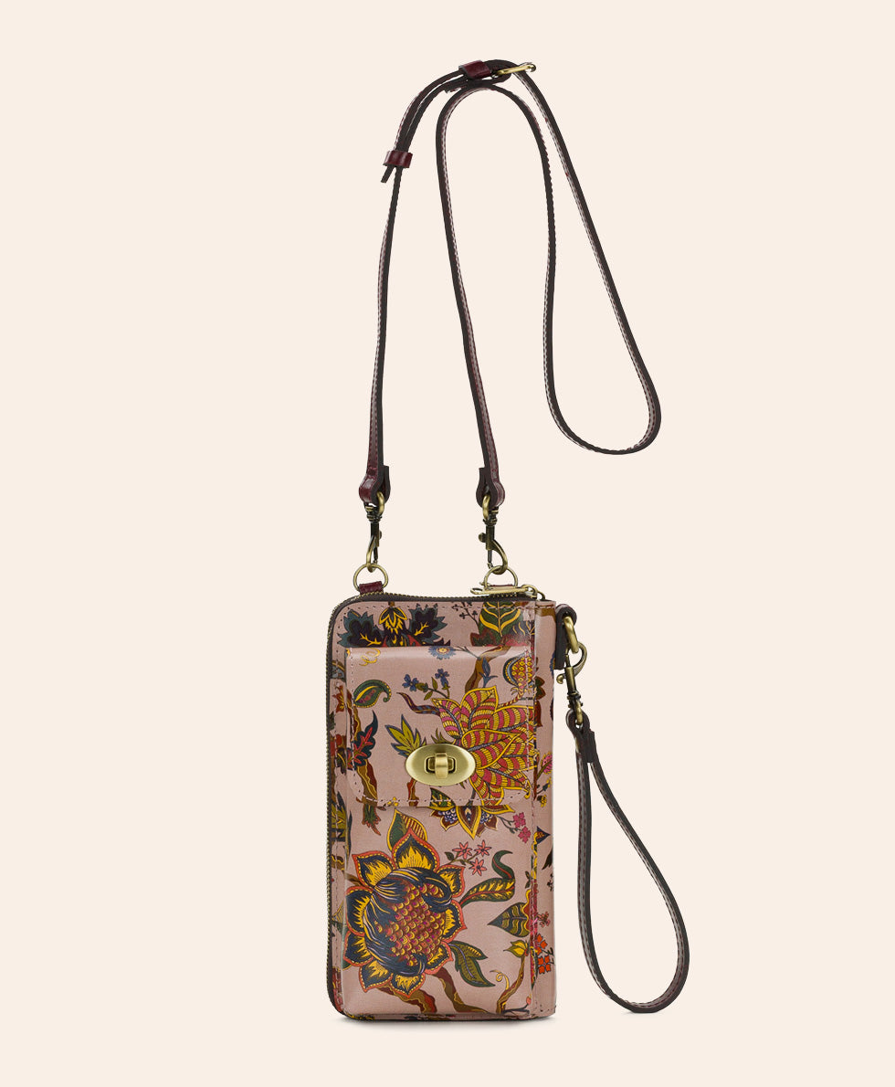A vertical crossbody phone pouch with a floral and bird pattern in earthy tones, featuring a dark brown leather strap and a gold-tone turn-lock closure, set against a solid cream background.