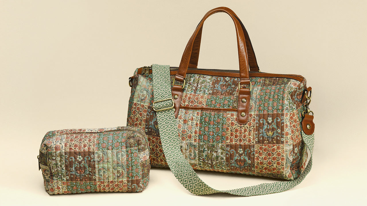 A quilted patchwork duffel bag with brown leather handles and trim, shown alongside a matching zippered pouch. The fabric features a multicolor patchwork pattern of teal, green, brown, and beige.