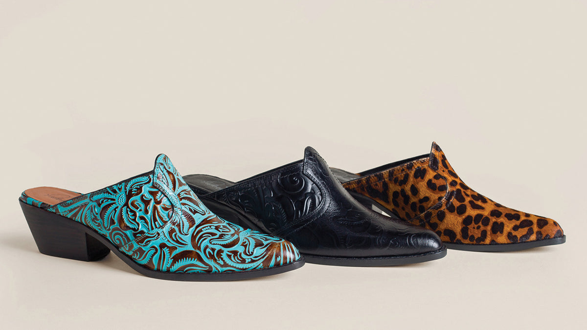 Three pointed-toe mule heels on a warm beige studio background: a turquoise and brown embossed patterned shoe in front, a black embossed shoe in the middle, and a brown-and-black leopard-print shoe behind.